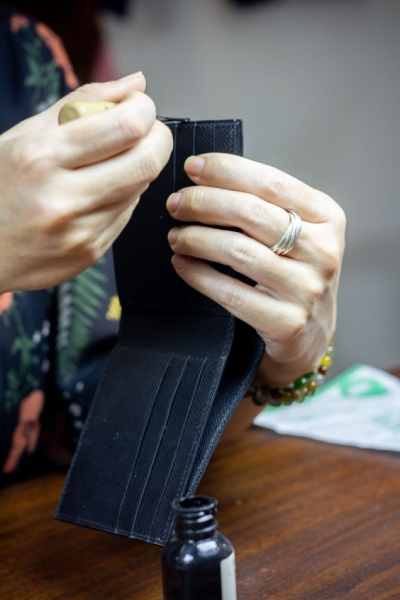 Người thợ burnishing hoàn thiện cạnh da bằng tay Người thợ burnishing hoàn thiện cạnh da bằng tay